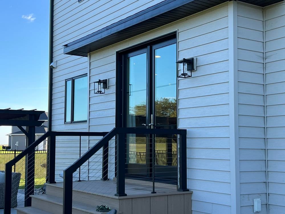 Modern home entrance with sleek double doors, handrails, and stylish outdoor lighting.