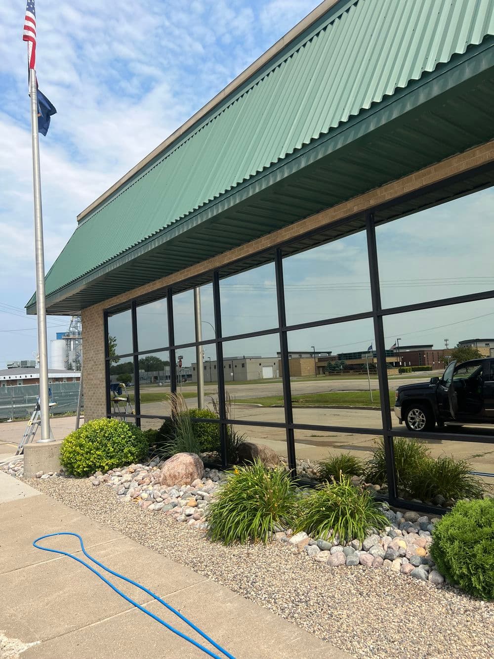 Modern building exterior with green roof, large windows, and landscaped garden.