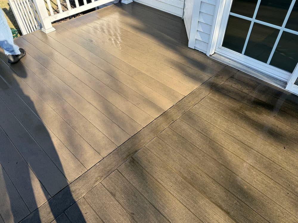 Clean wooden deck with a visible transition to an adjacent area and a person's shadow.