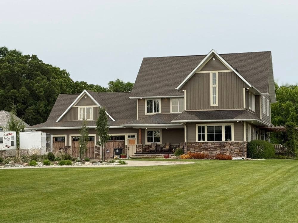 Modern two-story house with stone accents and landscaped lawn. Ideal family home design.